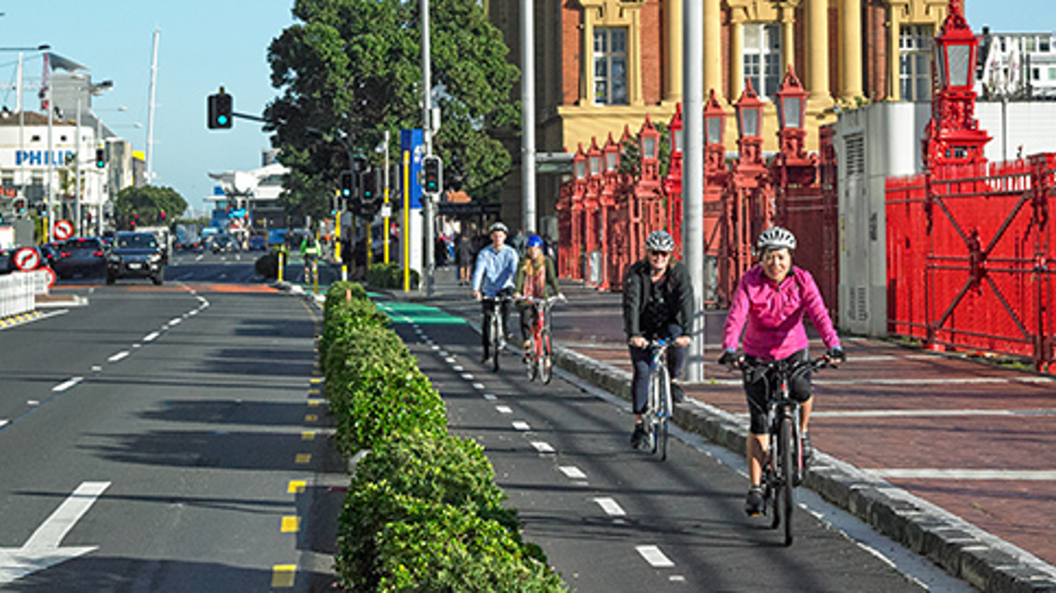 Cyclists ride bikes along a protected cycleway on Quay Street by Auckland ferry terminal.