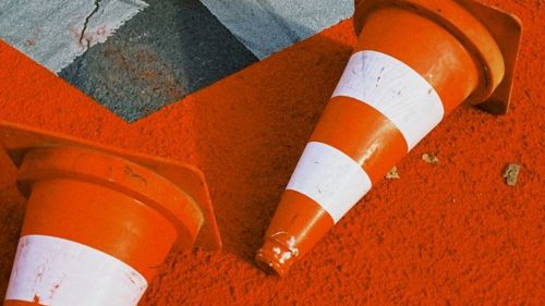 A close up of two orange road cones lying sideways on the pavement.
